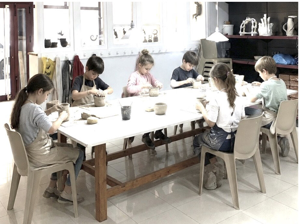 Grupo traballando a arxila arredor da mesa do taller
